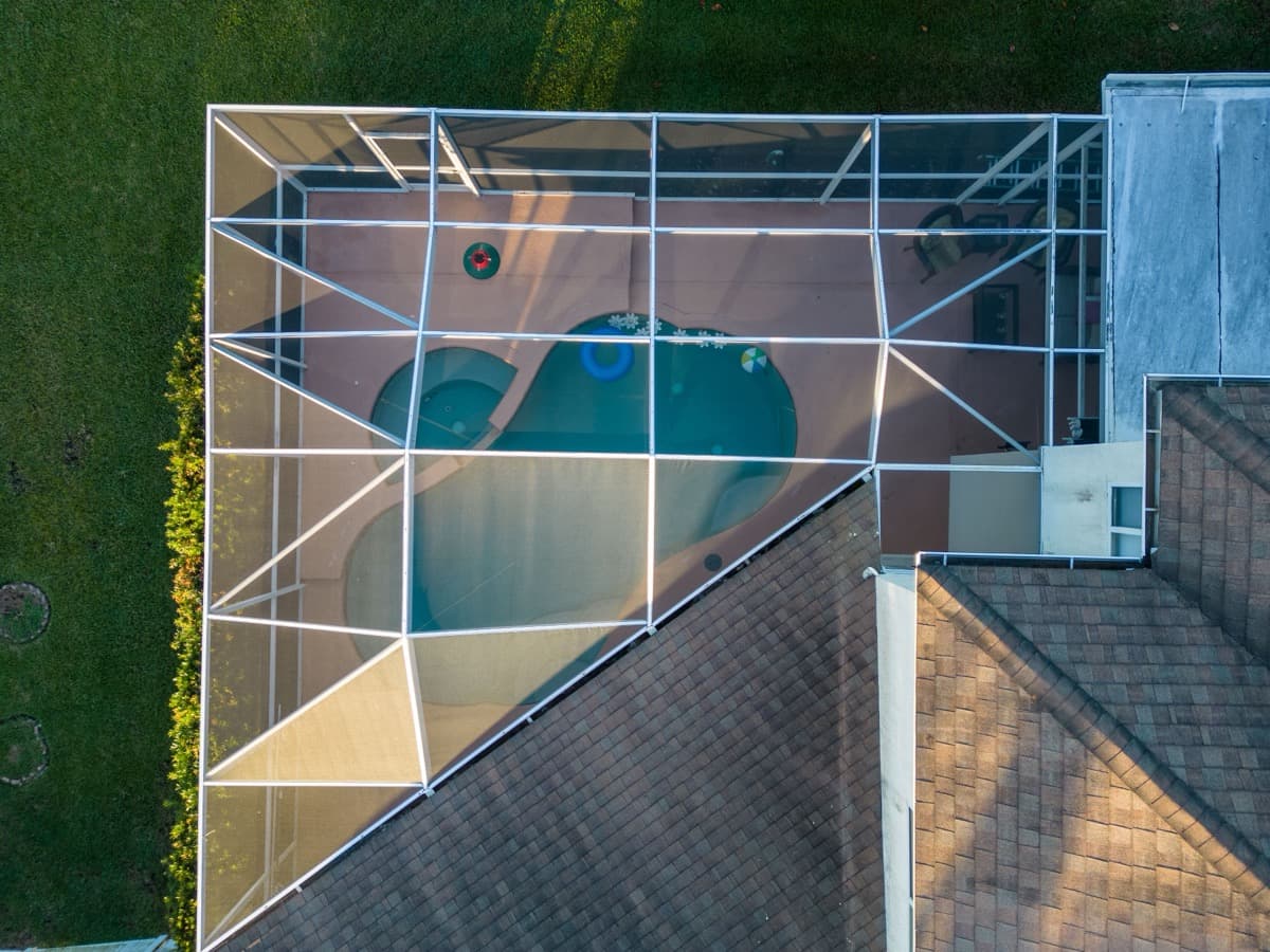 Drone shot of modern house with glass pool screen enclosure in South Florida